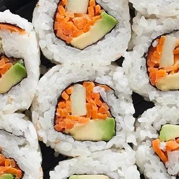 Close-up view of sushi rolls filled with avocado, carrots, and cucumber.