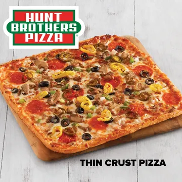 Thin crust pizza topped with olives, peppers, mushrooms, and pepperoni on a wooden board. Hunt Brothers Pizza logo at the top.